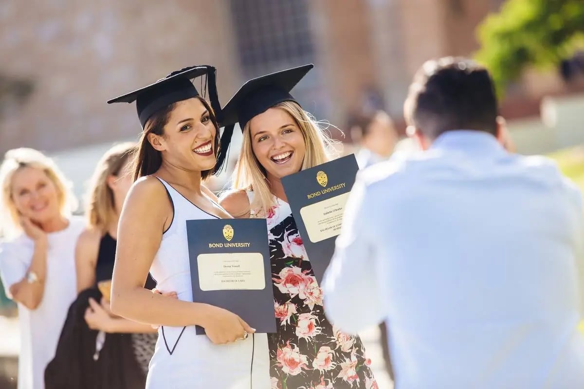 Zwei graduierende Studentinnen werden mit ihren Diplomen fotografiert
