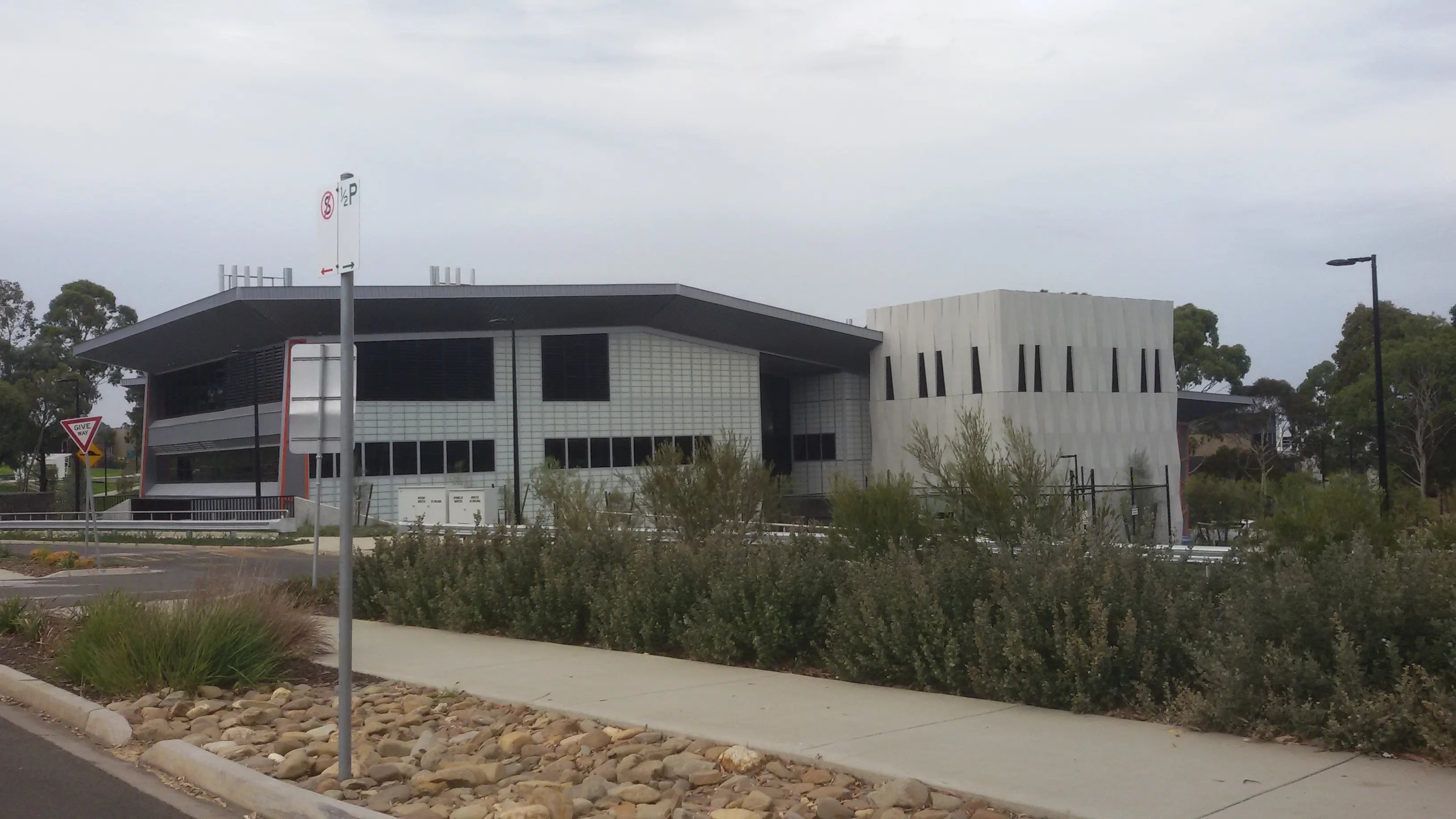 Ein Universitätsgebäude der Deakin University, umgeben von Büschen und klaren Wegen.