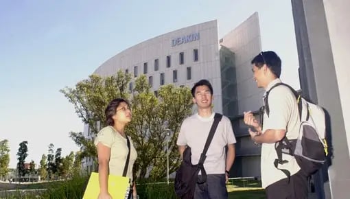 Drei Studierende auf dem Campus der Deakin University vor modernen Universitätsgebäuden.