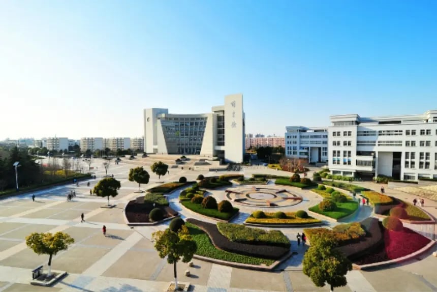 uftaufnahme des modernen Hauptcampus der Shanghai University mit architektonisch ansprechenden Gebäuden und kreisförmiger Parkanlage.