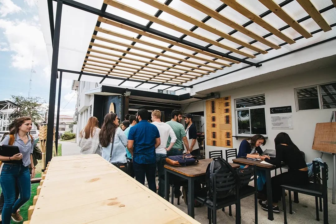 Studierende stehen und sitzen im Außenbereich der Universidad Veritas