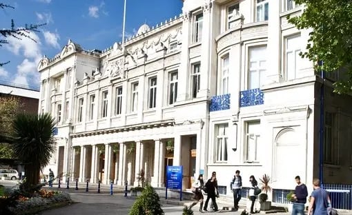 Der Campus der Queen Mary University of London mit einer beeindruckenden Fassade und Studierenden, die den Vorplatz nutzen.