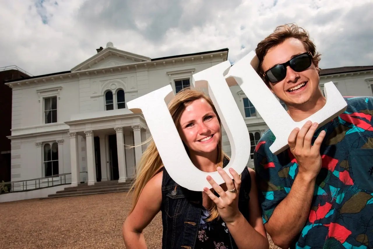 Zwei Studierende der University of Limerick lächeln und halten die Initialen der Universität