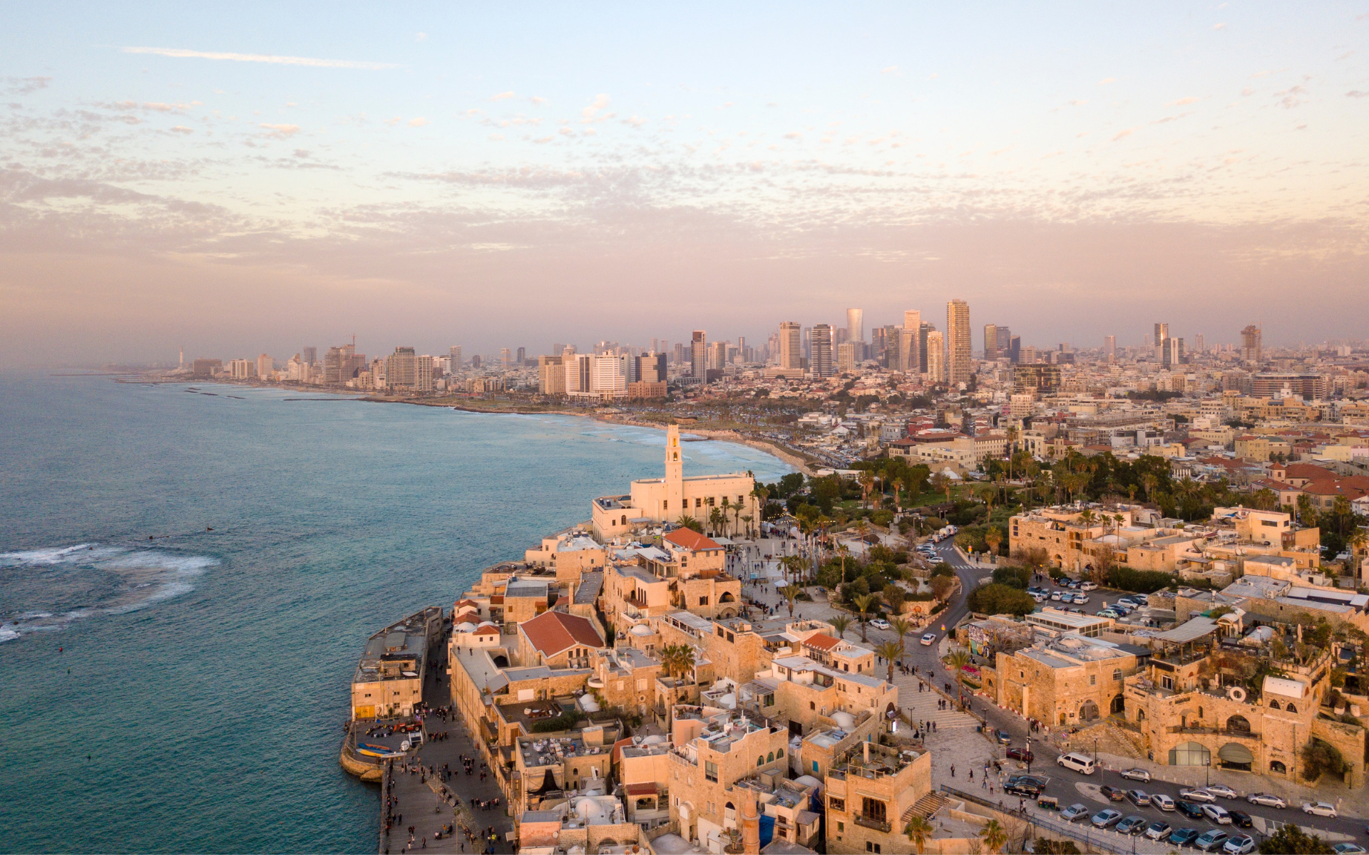 Blick auf die Skyline von Tel Aviv, Israel, während des Sonnenuntergangs, mit der historischen Altstadt von Jaffa im Vordergrund. 