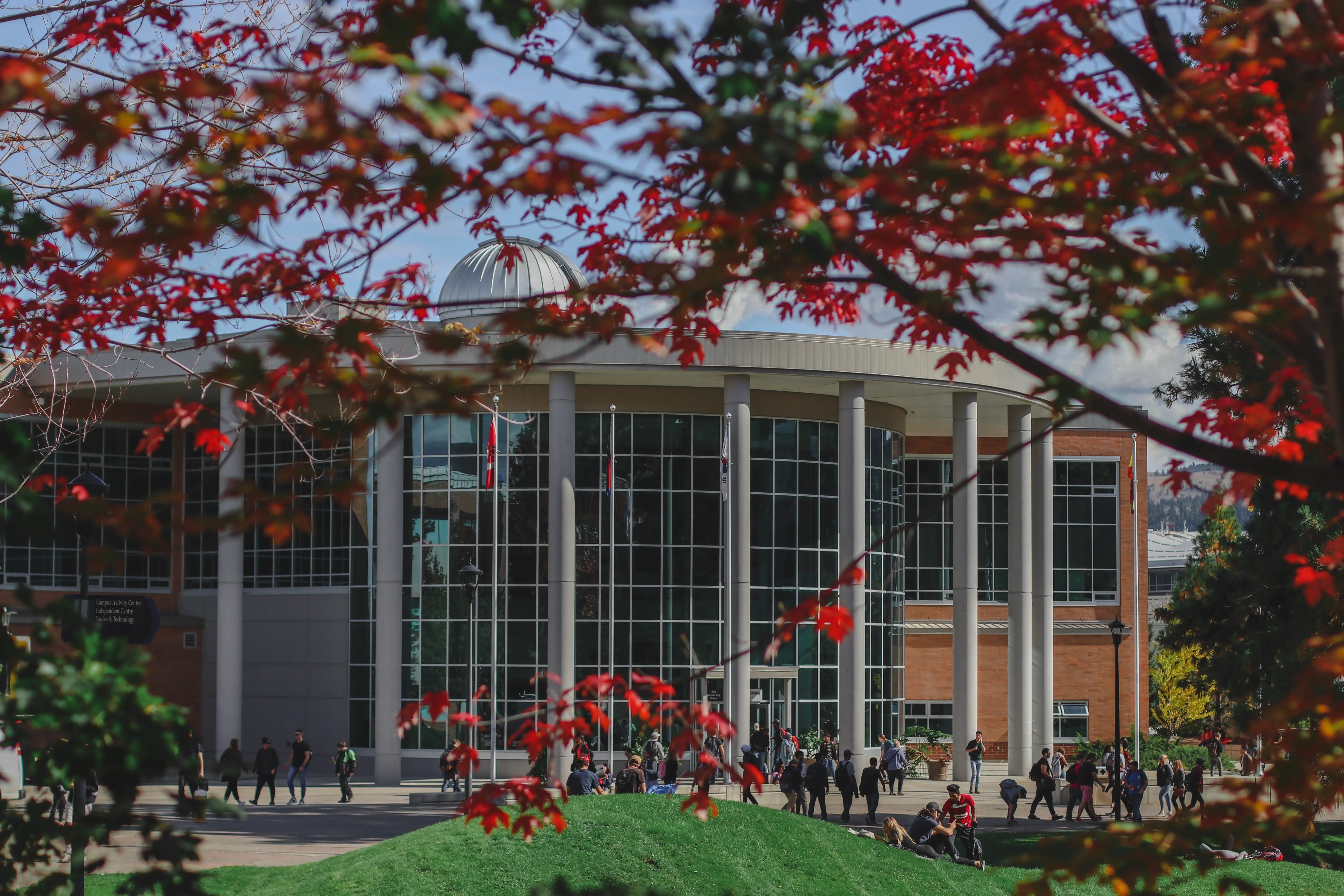 Hauptgebäude der Thompson Rivers University, umrahmt von roten Herbstblättern.