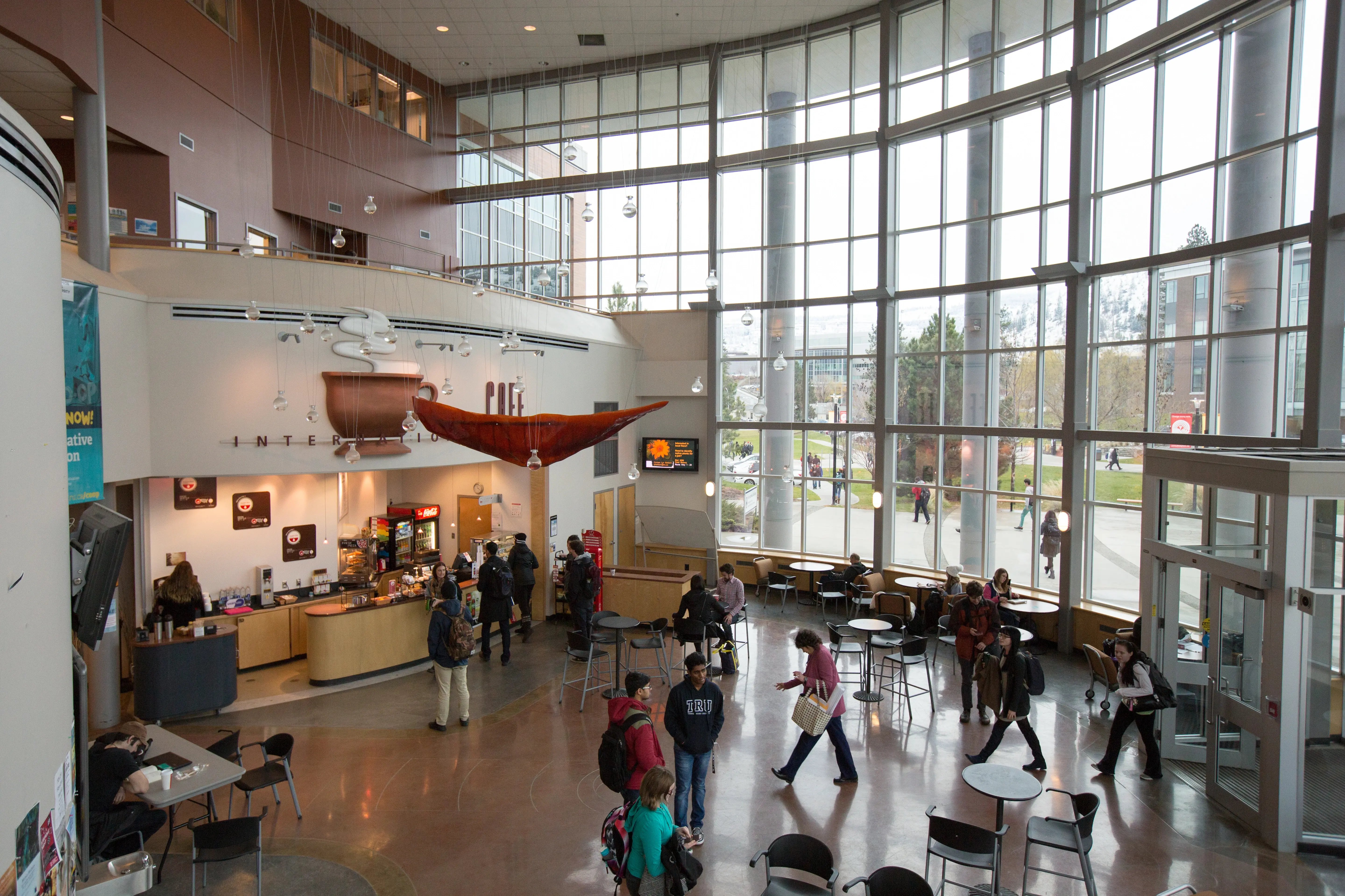 Lichtdurchflutetes Atrium der Thompson Rivers University mit Studierenden und Sitzbereichen.