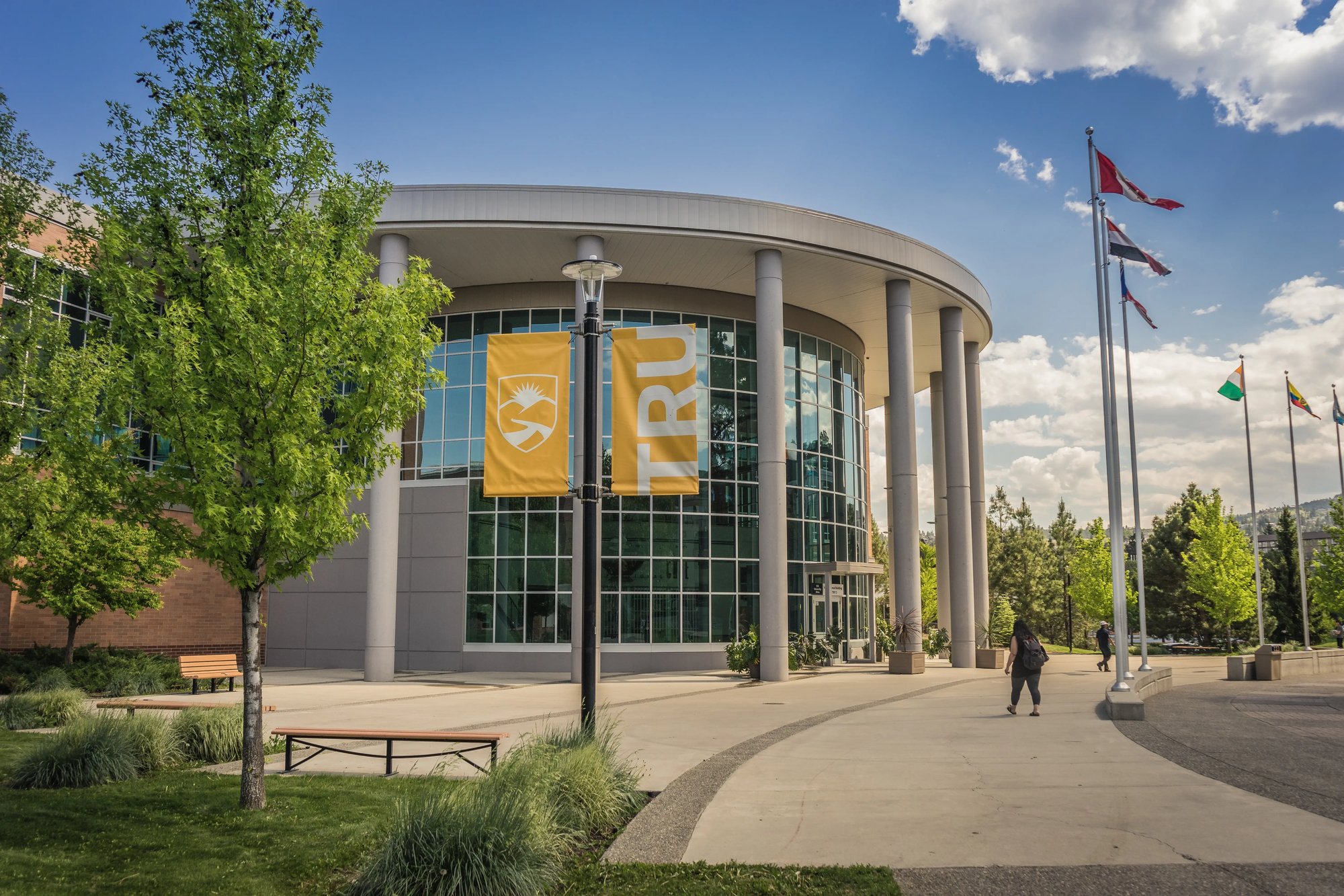 Haupteingang der Thompson Rivers University mit Studierenden und Fahnen.