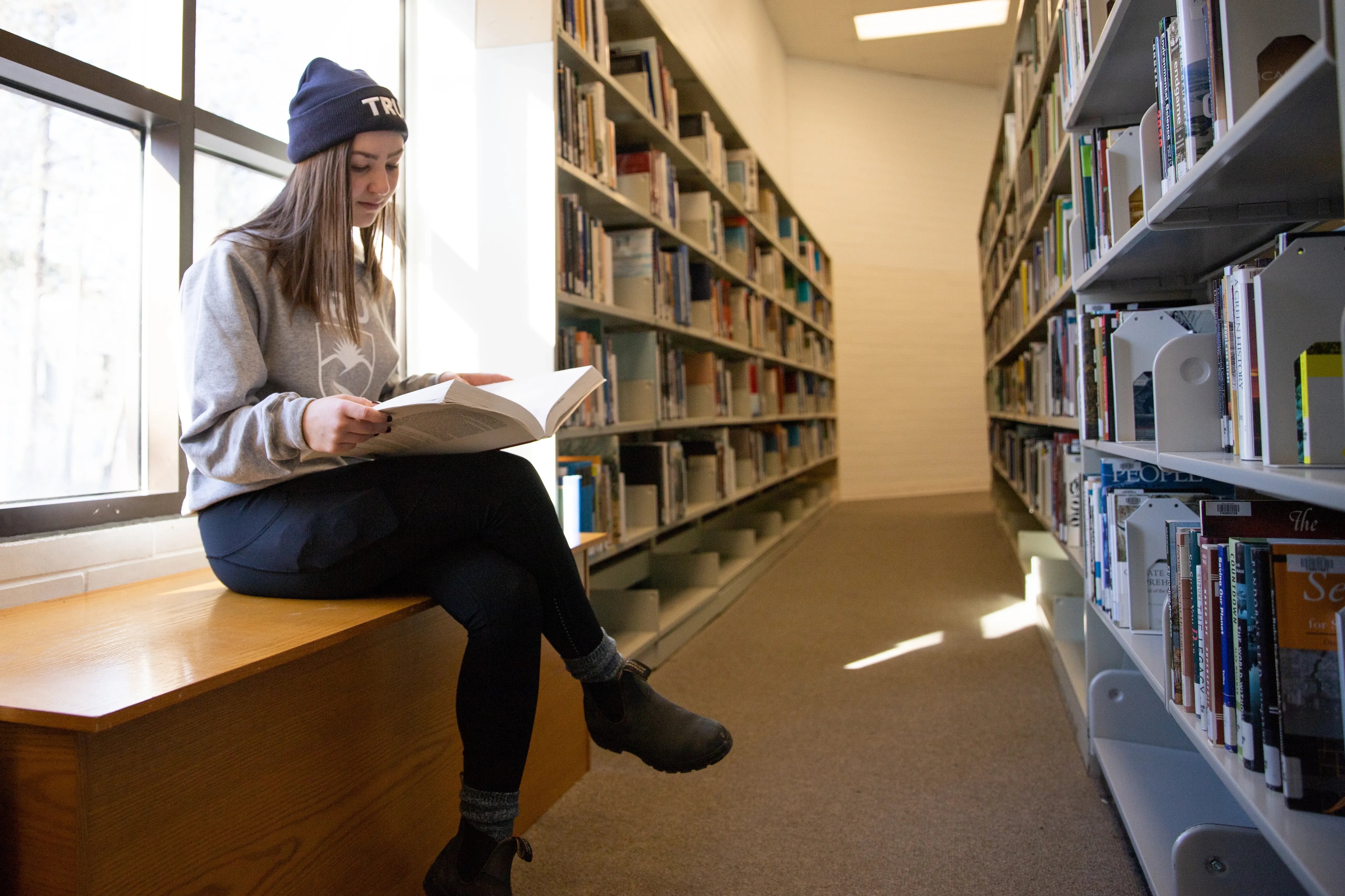 Studentin liest ein Buch in der Bibliothek der Thompson Rivers University.