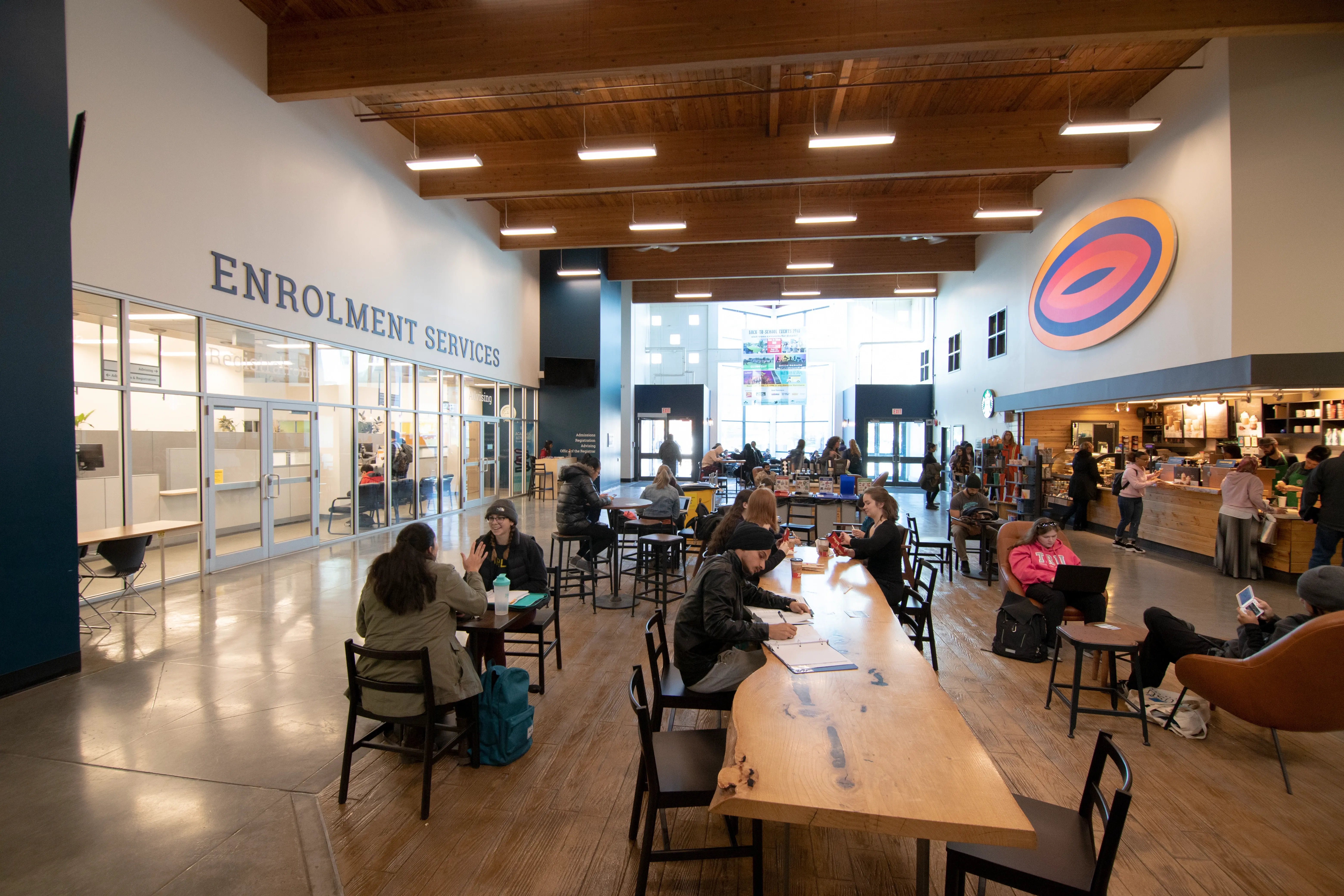 Cafeteria der Thompson Rivers University mit Studierenden an Tischen und in Gesprächsrunden.