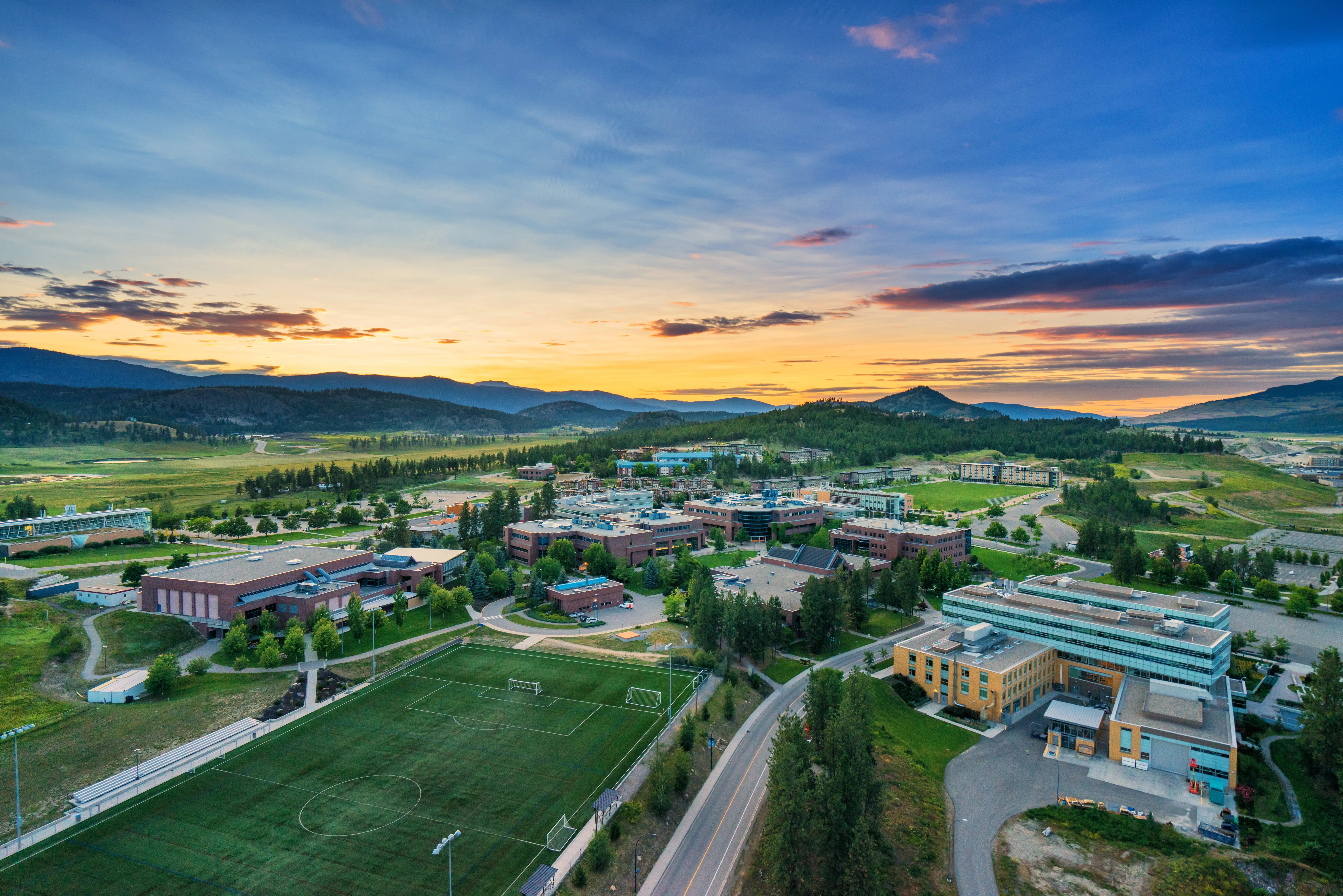 Ein Panorama Blick auf den Campus der University of British Columbia in Vancouver mit den Bergen und einem Sonnenuntergang im Hintergrund