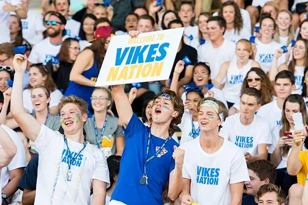 Jubelnde Studierende der University of Victoria in blau-weißen Shirts bei einer Sportveranstaltung