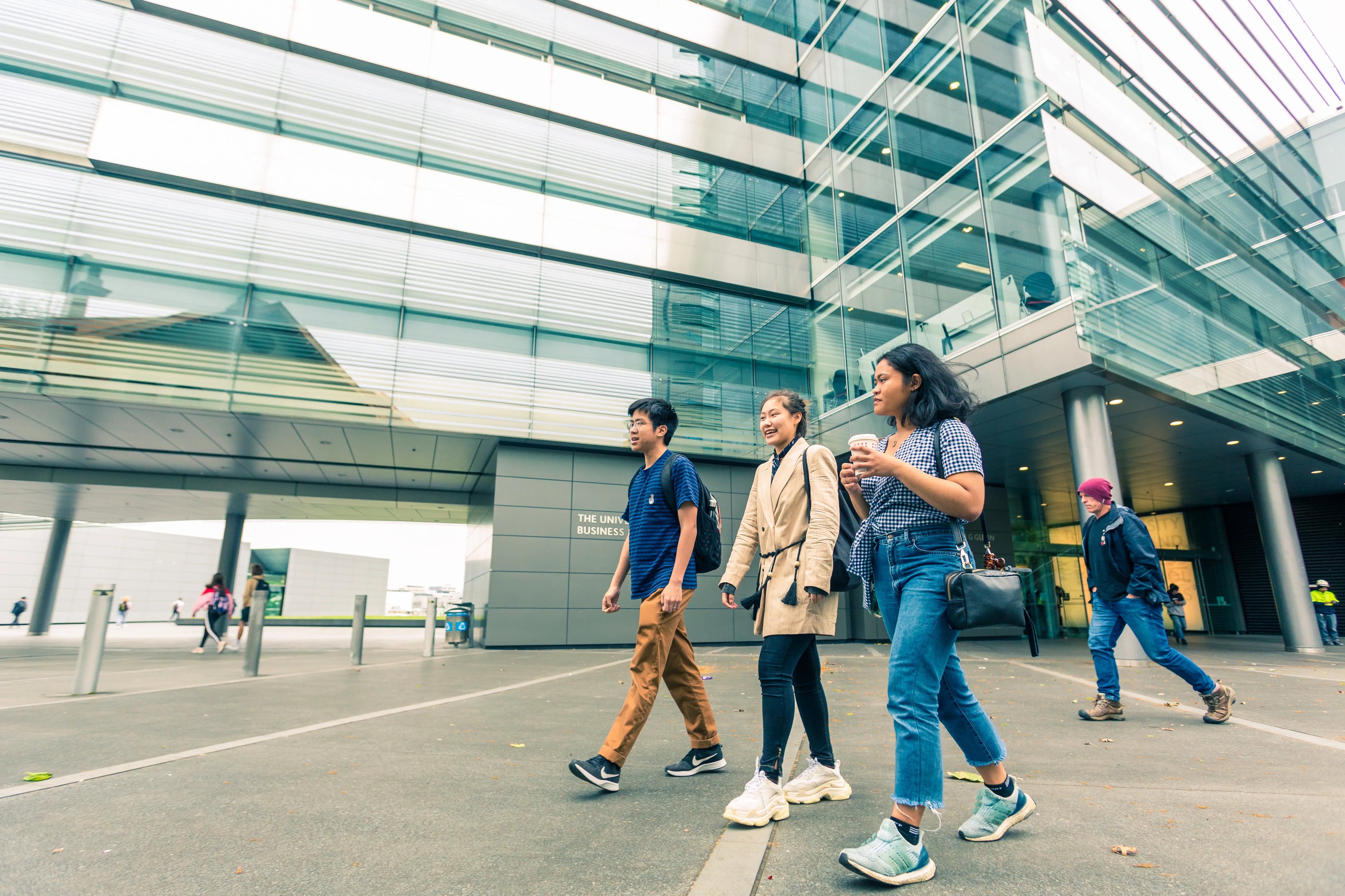 Drei Studierende der University of Auckland laufen am Campus
