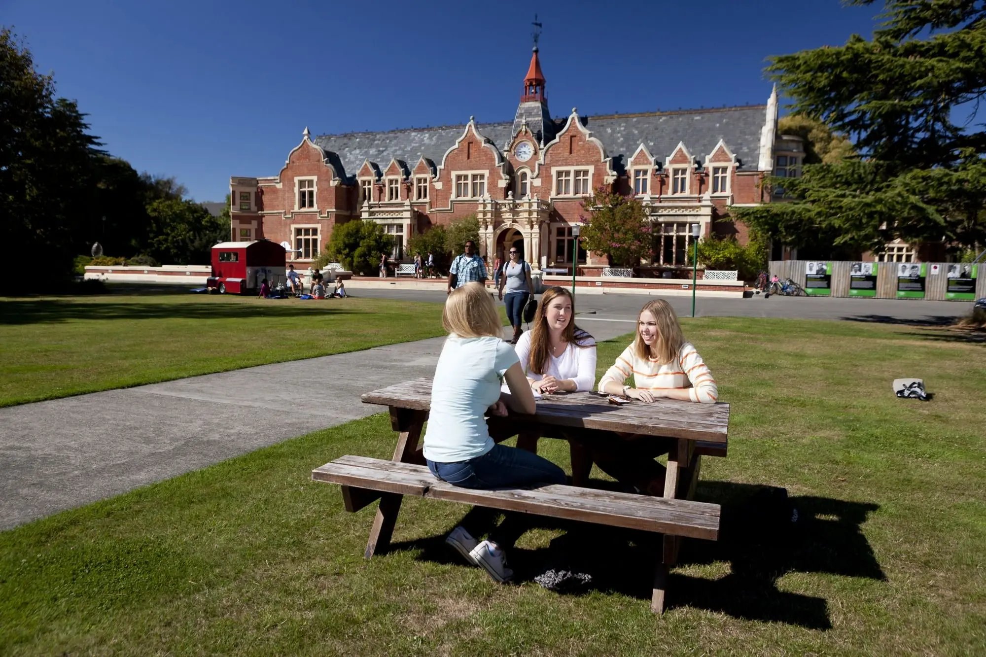 Drei Studierende sitzen im Vorgarten der Lincoln University an einem Tisch