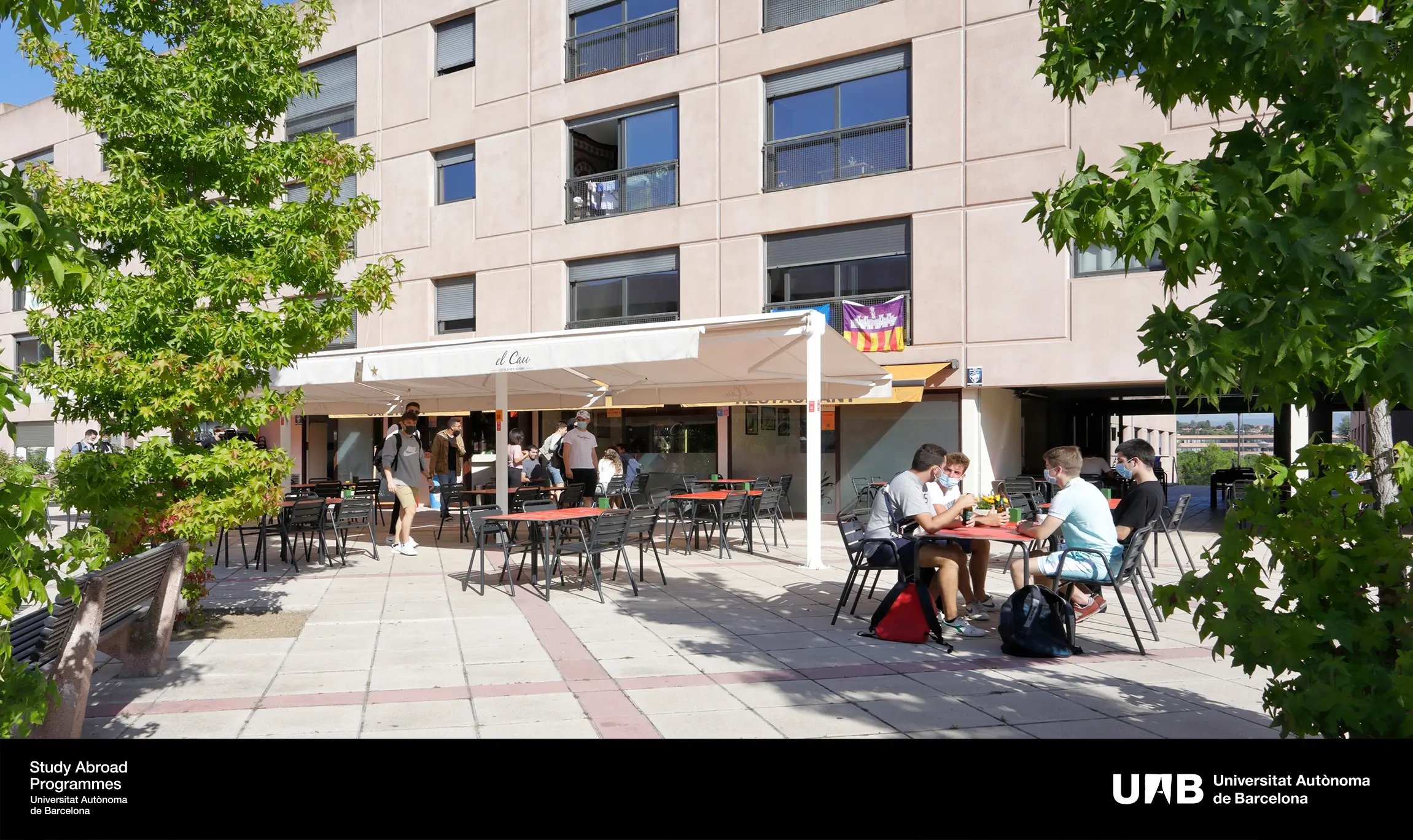 Studierende sitzen im Außenbereich der Mensa der Universitat Autònoma de Barcelona