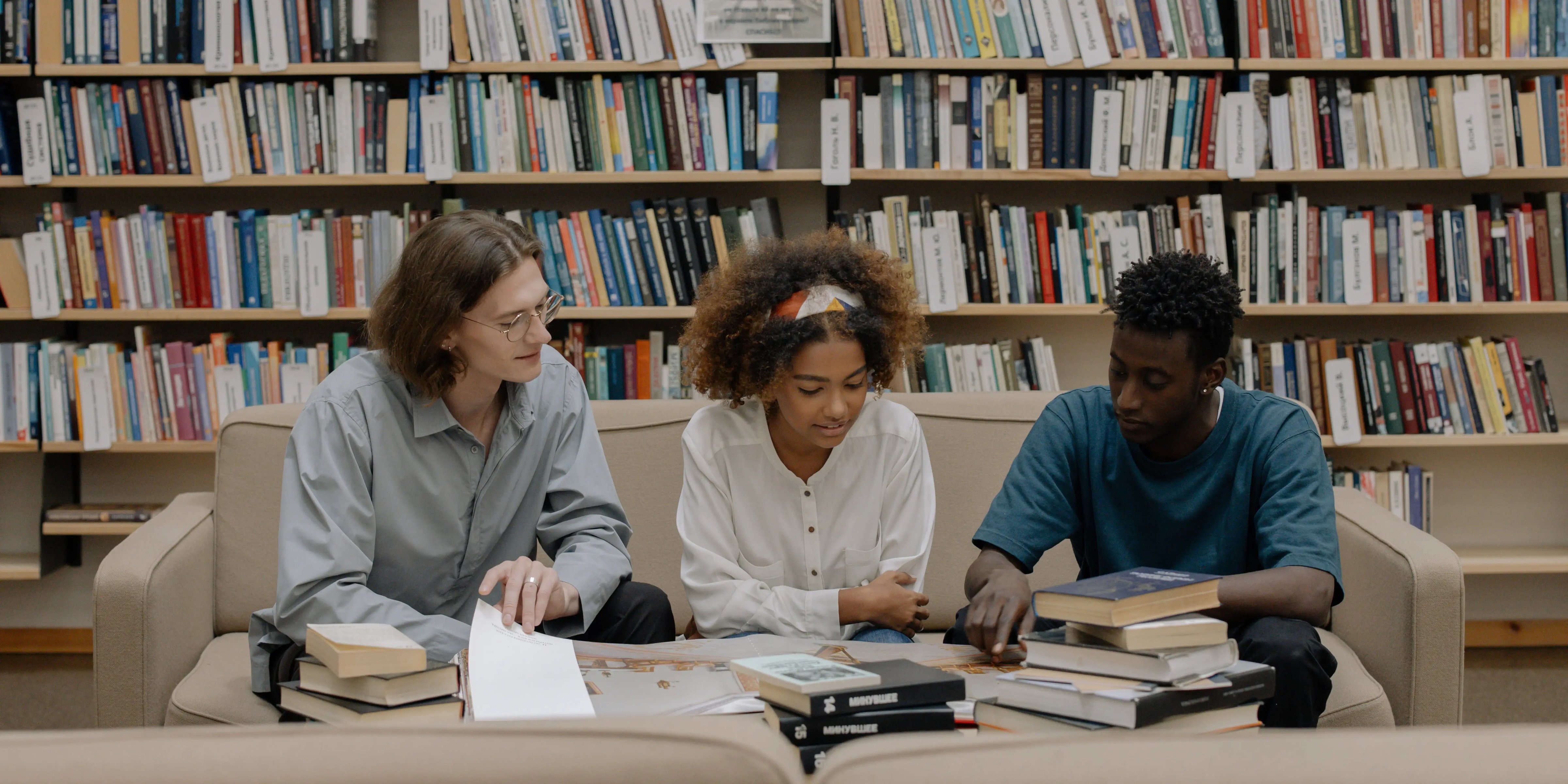 Drei internationale Studierende lernen gemeinsam in einer Bibliothek während ihres Auslandssemesters.