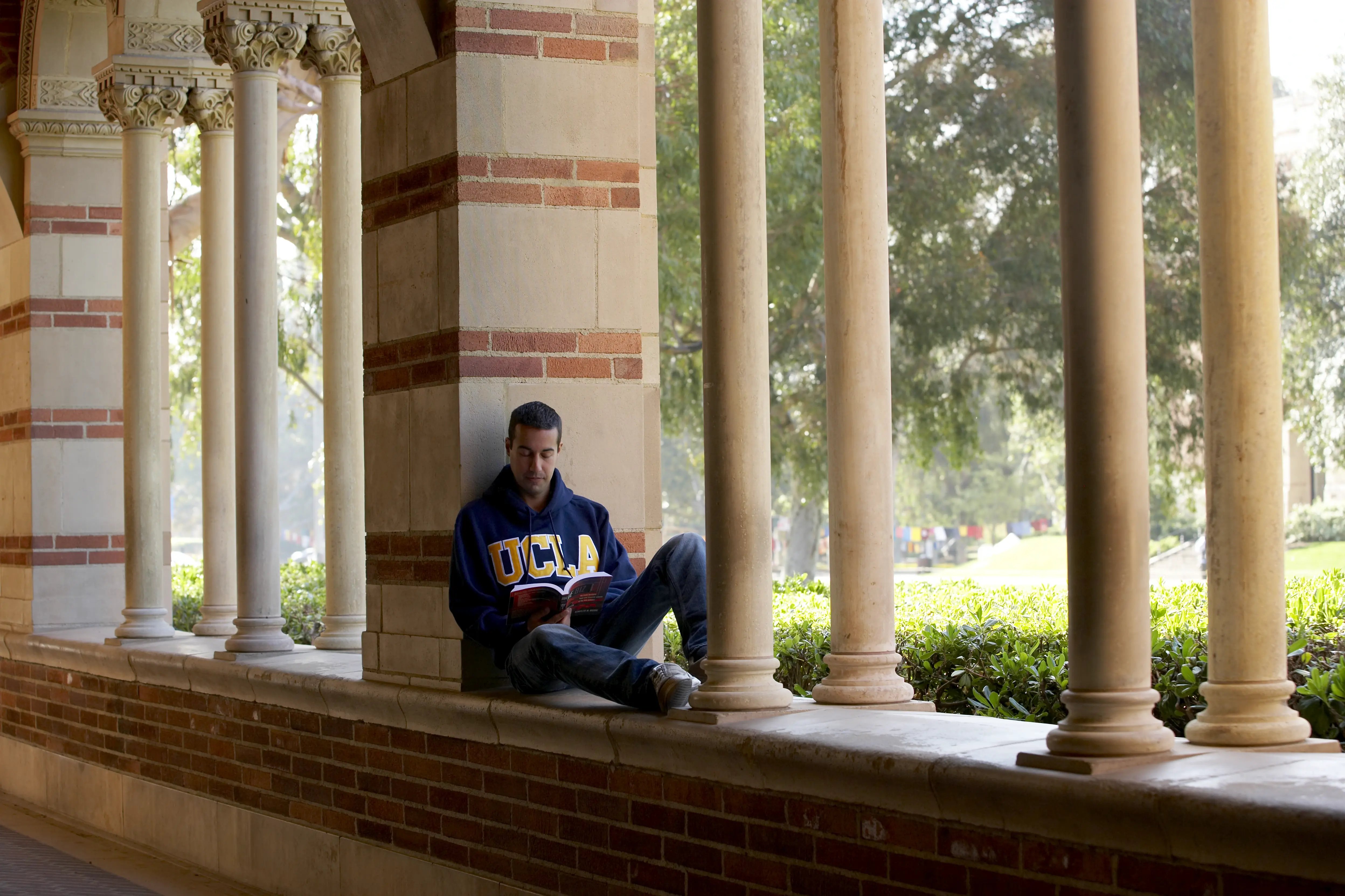 Student im UCLA-Pullover liest auf dem Campus der University of California, Los Angeles. 