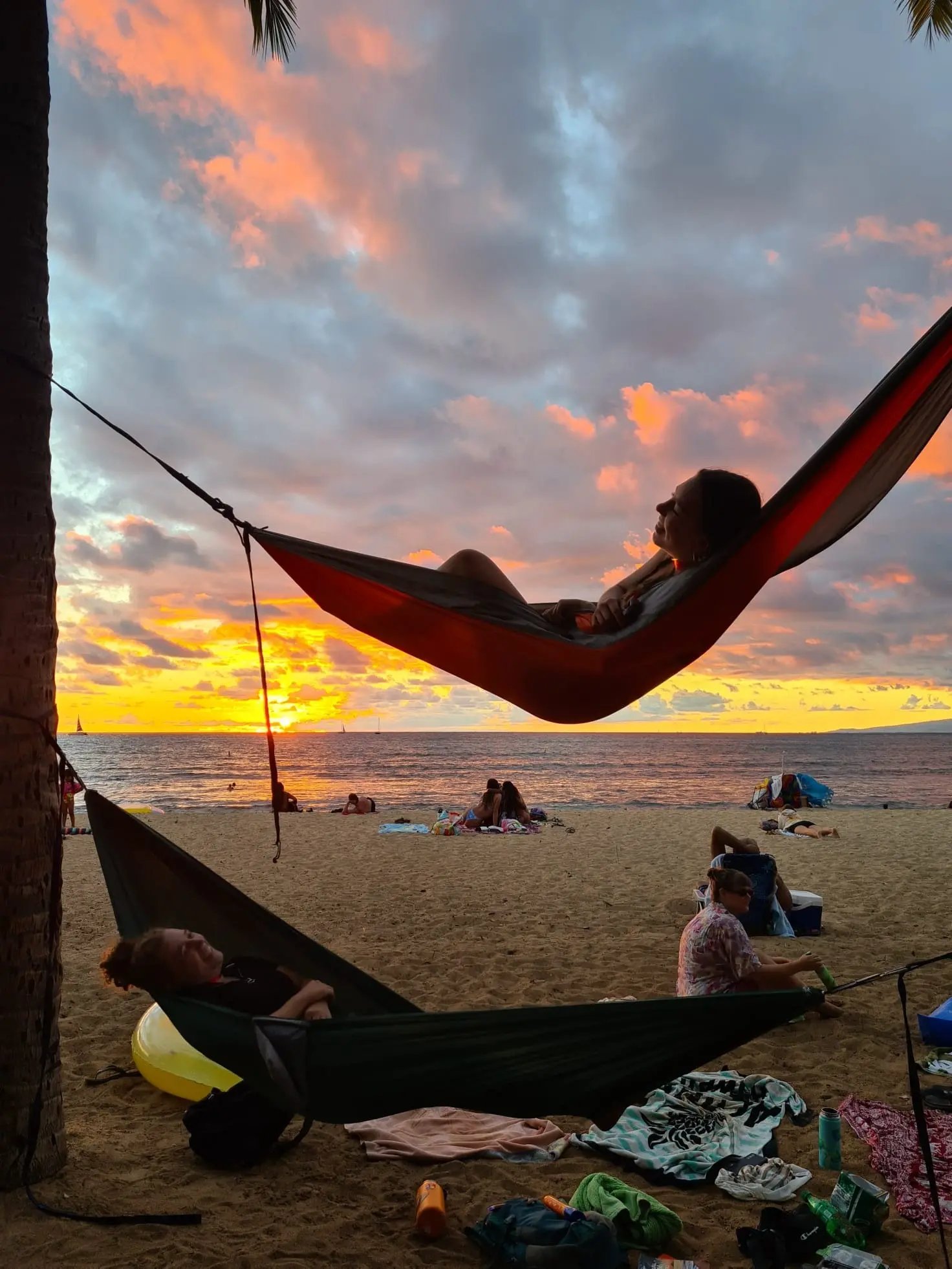 Person entspannt in einer Hängematte am Strand bei Sonnenuntergang.