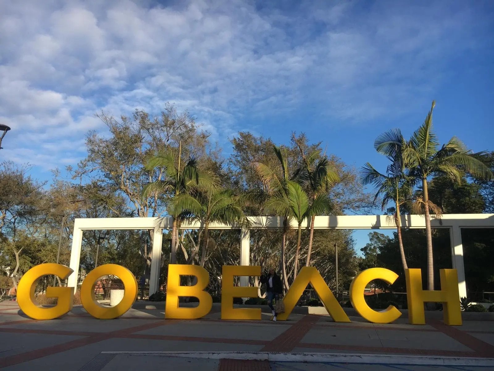 Eine Studentin der California State University, Long Beach steht vor dem "GO BEACH" Schild