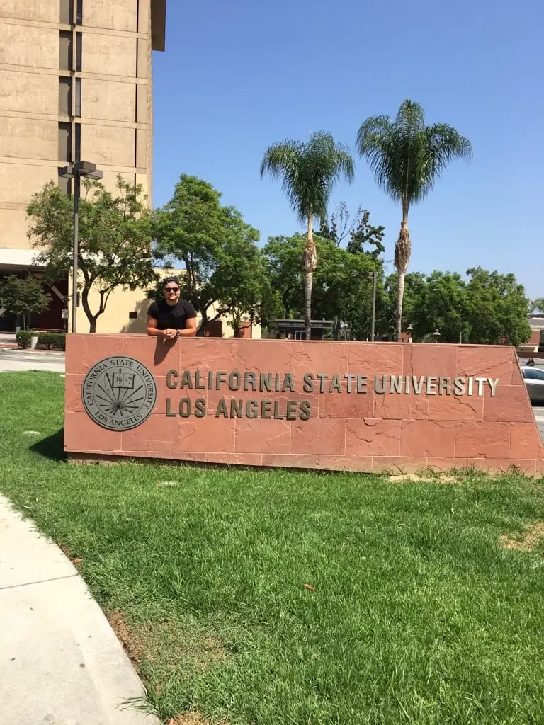 Ein Student steht am Eingangsschild der California State University, Los Angeles