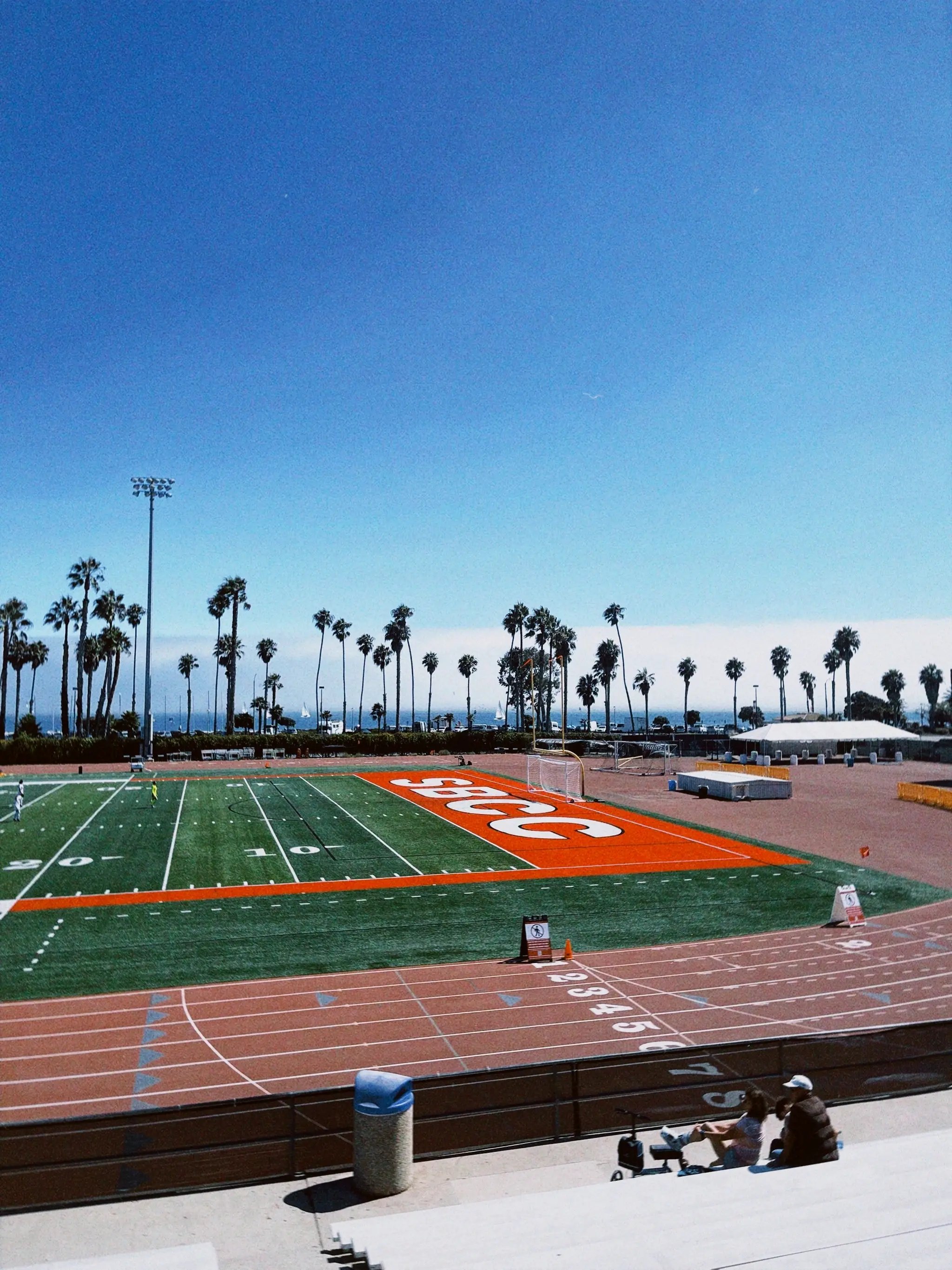 Der Sportplatz des Santa Barbara City College mit dem Schriftzug „SBCC“ und Palmen im Hintergrund.